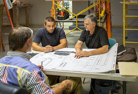  Group of men around a set of plans on a table 