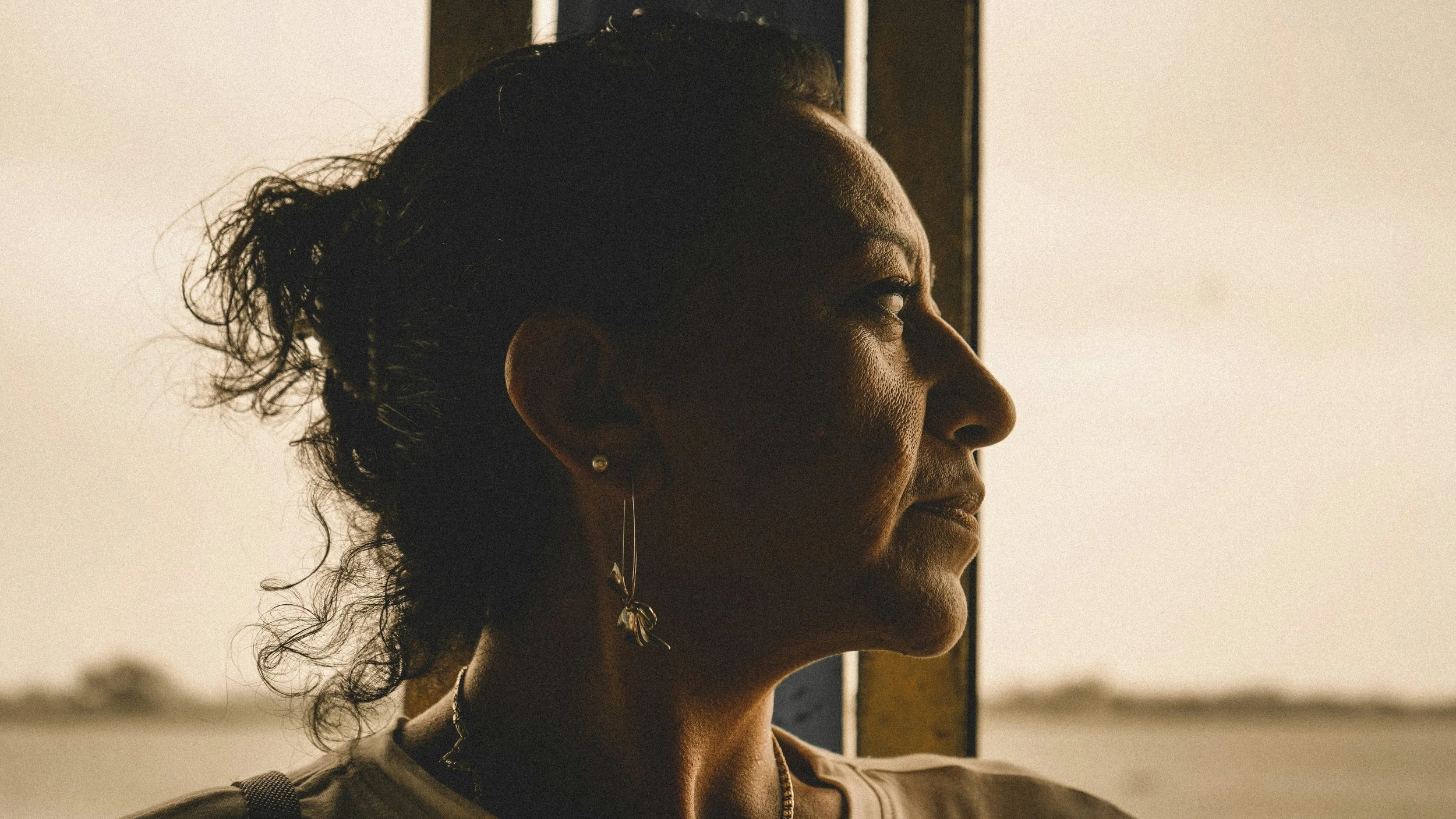 Woman of colour in profile looking toward the light in quiet reflection — trauma and culturally-informed therapy in Burnaby, BC