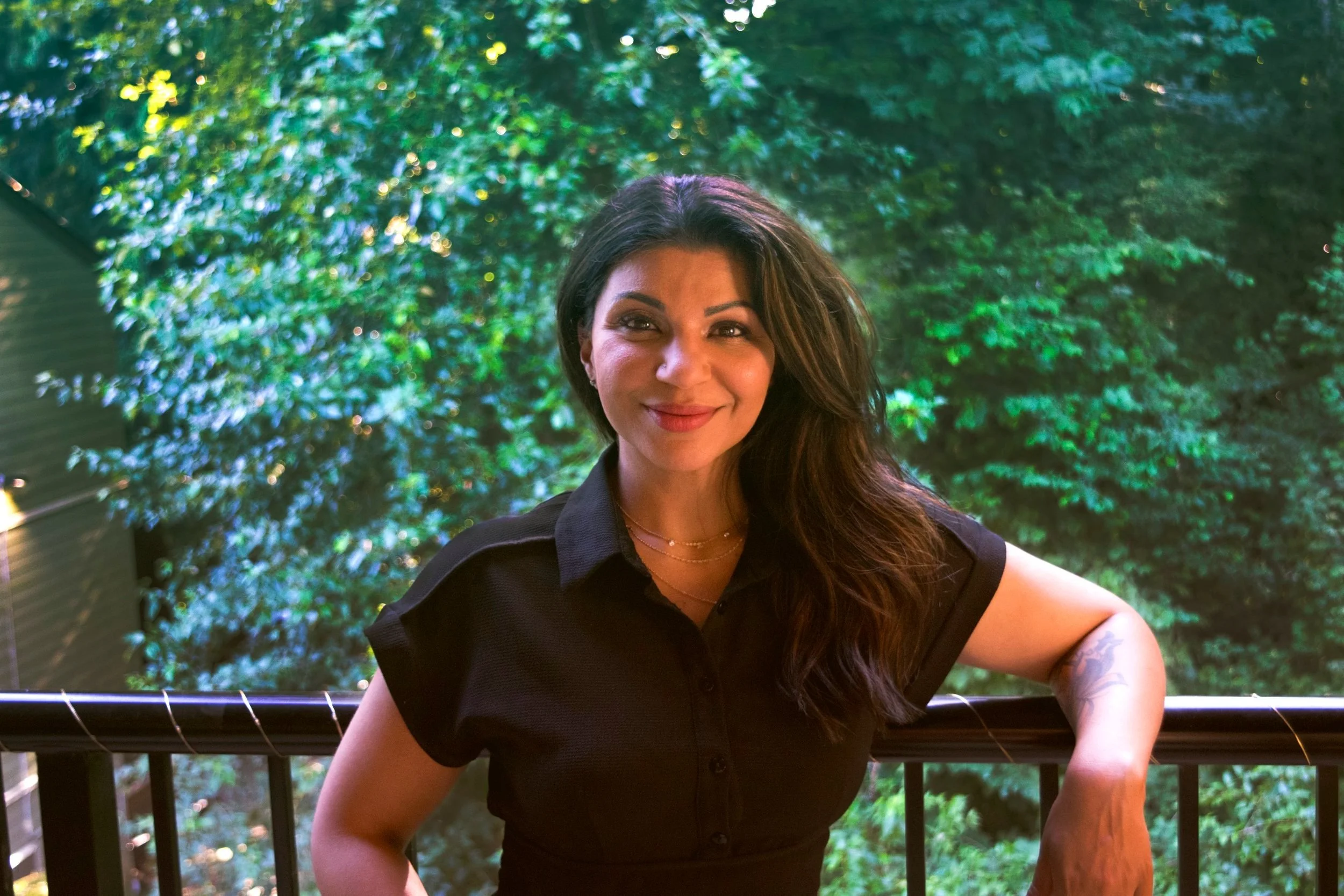 Nashina Merani, Registered Therapeutic Counsellor at Harbour Counselling & Wellness, smiling outdoors surrounded by greenery in Burnaby, BC