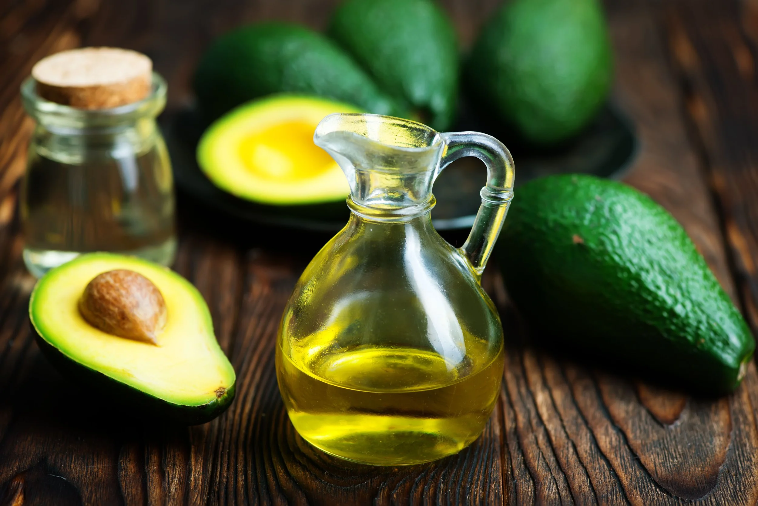 Avocats et bouteille d’huile d’olive sur une table en bois