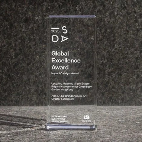 Clear glass award with engraved text for the 2025 Global Excellence Award by Impact Catalyst, presented to Upcycling Maternity for set of diaper band and accessories for green baby garden in Hong Kong, signed by Alan T.F. Soh.