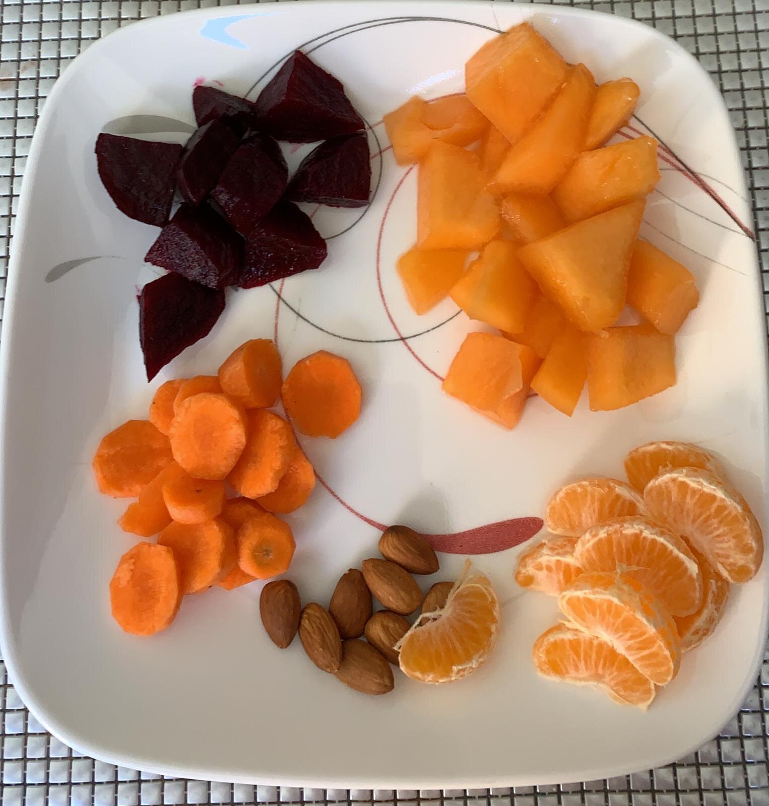 Plate with chopped beets, cantaloupe chunks, carrot slices, almonds, and mandarin orange segments.
