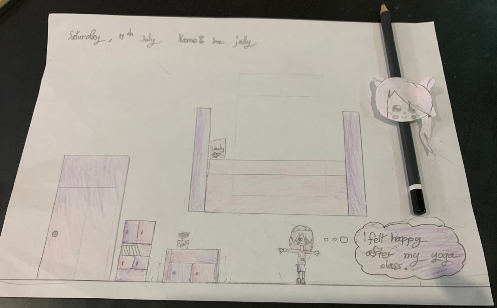 Child's drawing of a bedroom with furniture, a figure doing yoga, and a thought bubble saying "I felt happy after my yoga class," along with a pencil featuring a paper clip with a cartoon face attached.