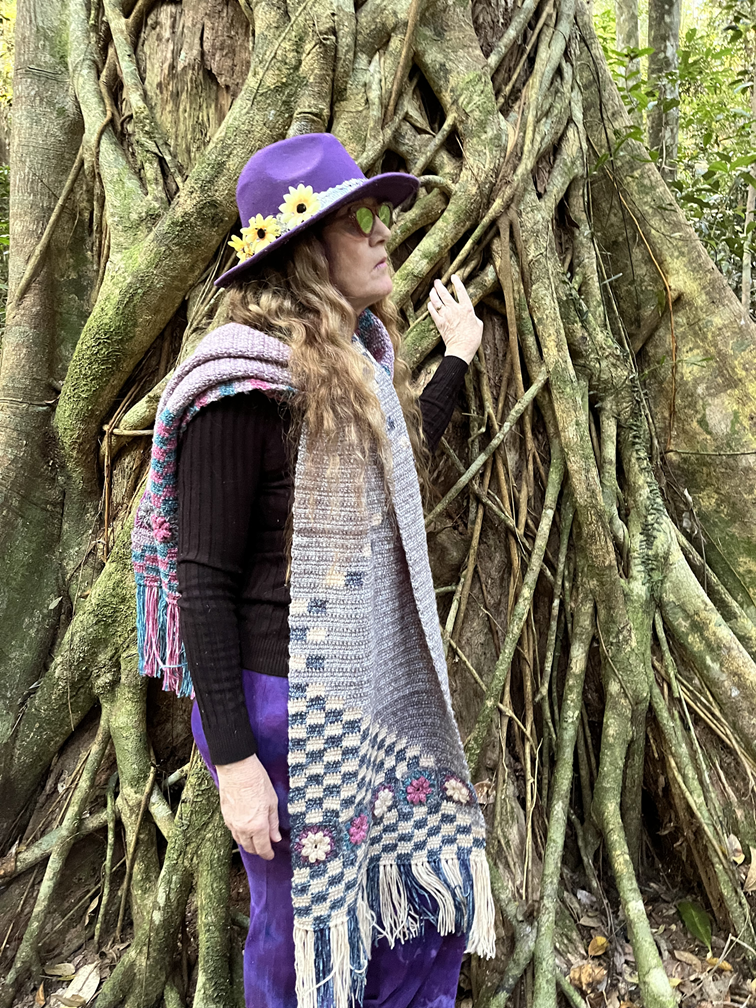 crochet shawl, linked double crochet with flowers and a checker pattern. shown modelled by woman in a rainforest
