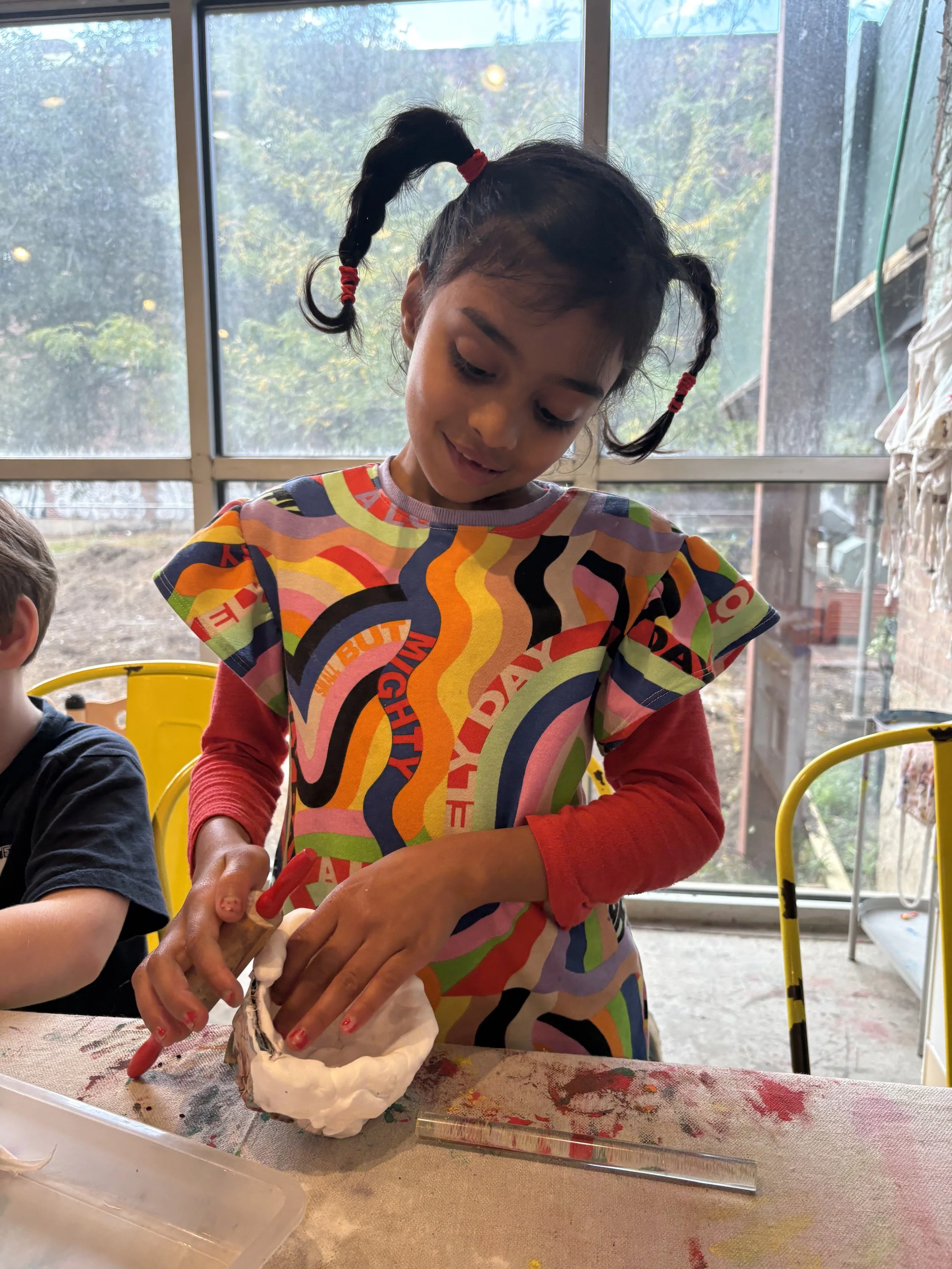 Model of a city skyline made from cardboard buildings with cut-out windows and doors.