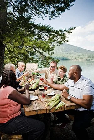 A group of mature people having a picnic by a lake