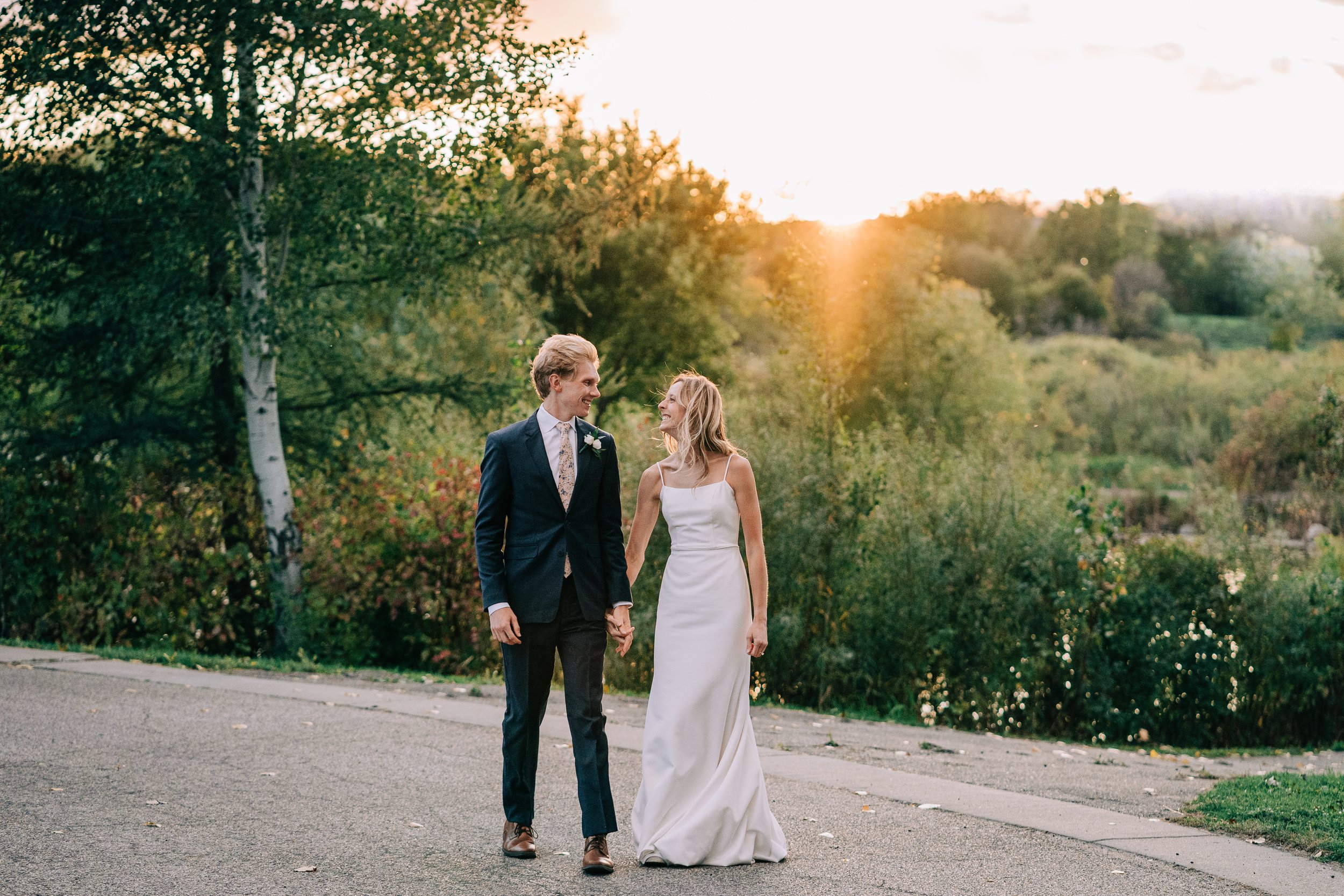 Bride and groom bumping hips and walking and smiling at sunset colored.jpg