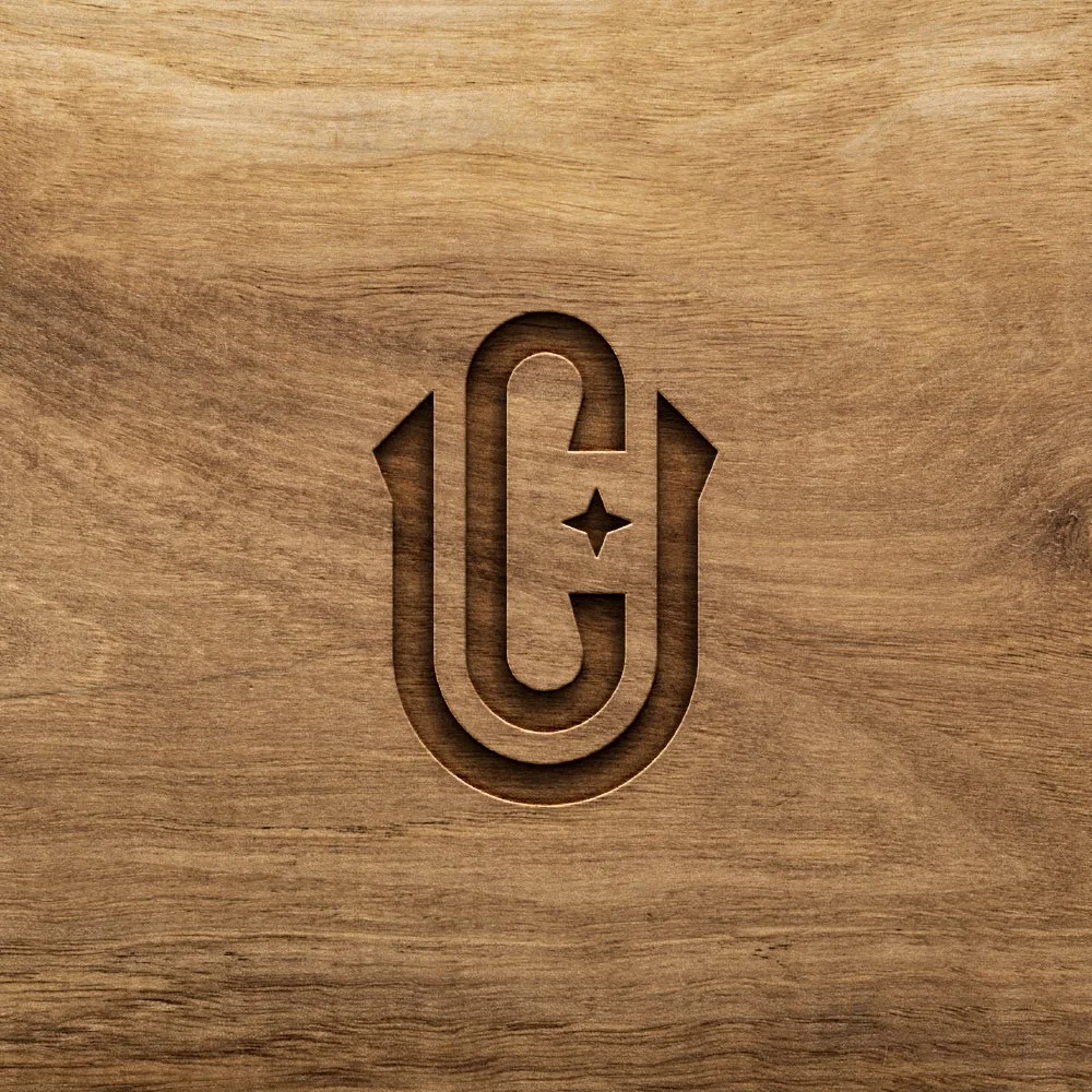 Wooden surface with a carved symbol resembling a paperclip with a star in the middle.