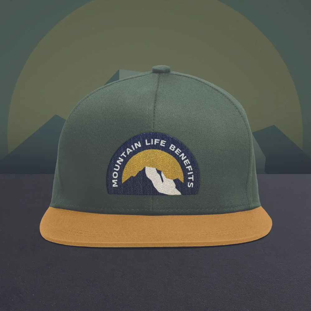 Green and yellow cap with mountain logo reading "Mountain Life Benefits" against mountain landscape background. Mount Moran.