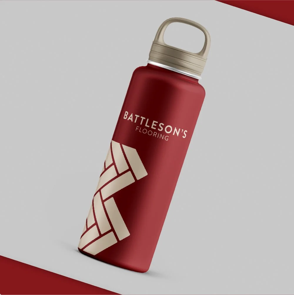 A red water bottle with a beige lid, branded with 'Battleson's Flooring' and a stylized pattern resembling floor tiles.