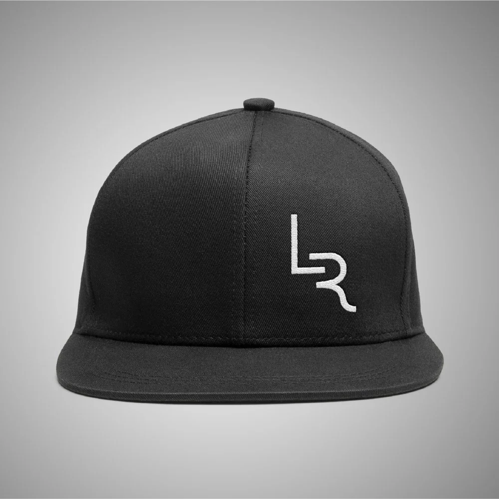 Black snapback hat with a white logo on the front against a gray background.