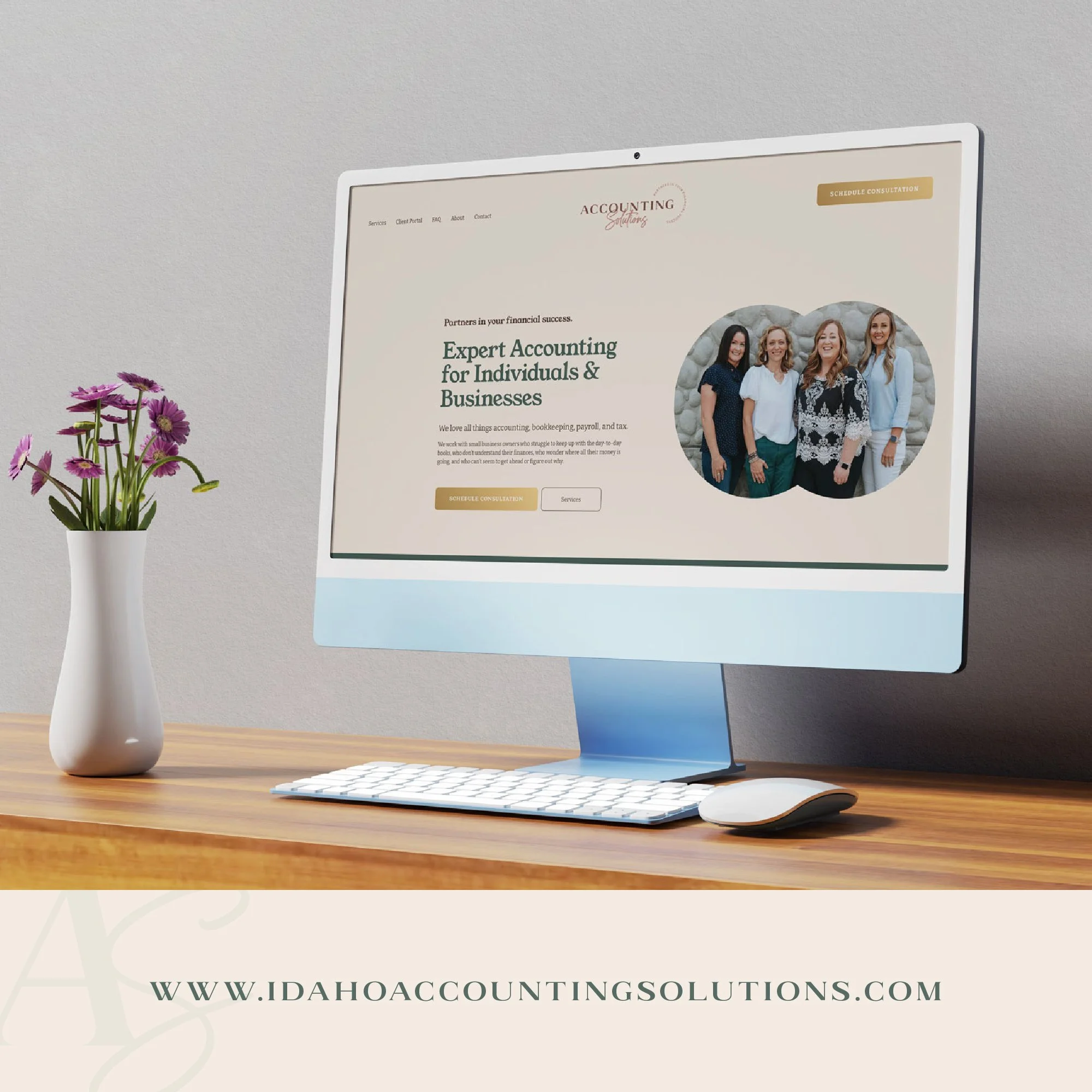 Computer monitor displaying a website for Idaho Accounting Solutions, with a photo of four women, a vase with purple flowers on a wooden desk.
