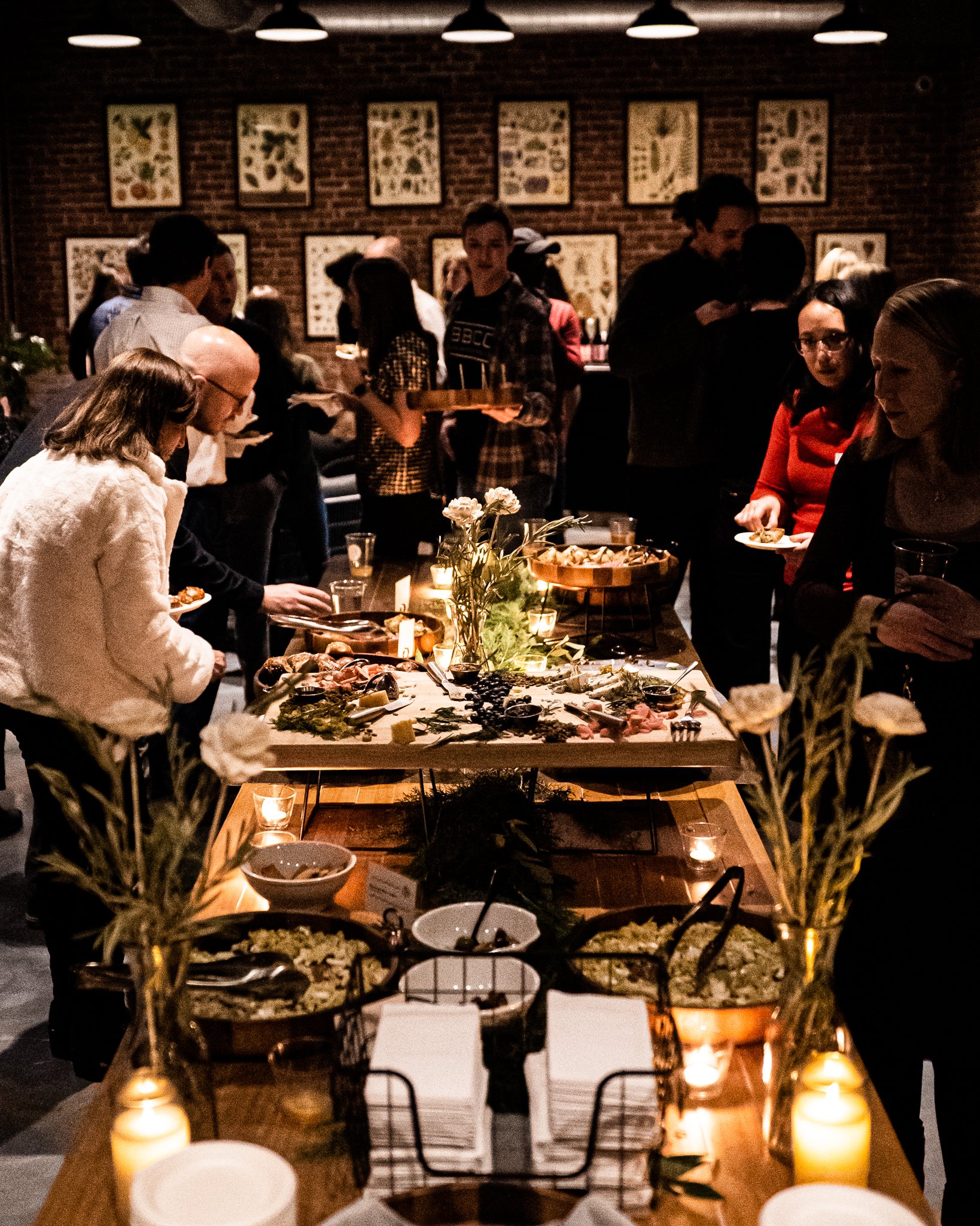 Guests sharing food around a candlelit table in Autochrome at Burlington Beer Co.