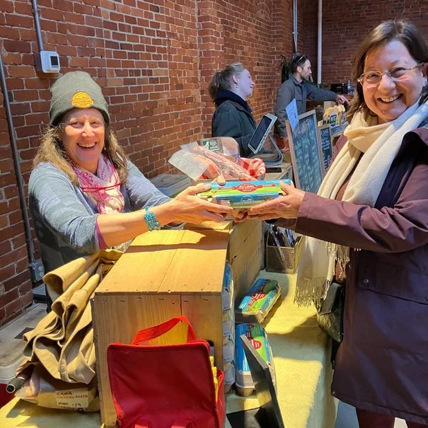 Vendor and customer at an indoor Burlington Farmers Market