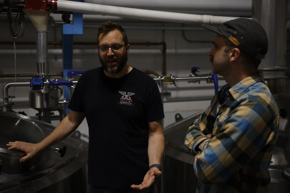 Two people beside brewing equipment in the SingleCut and Burlington Beer Co. collaboration photo archive.