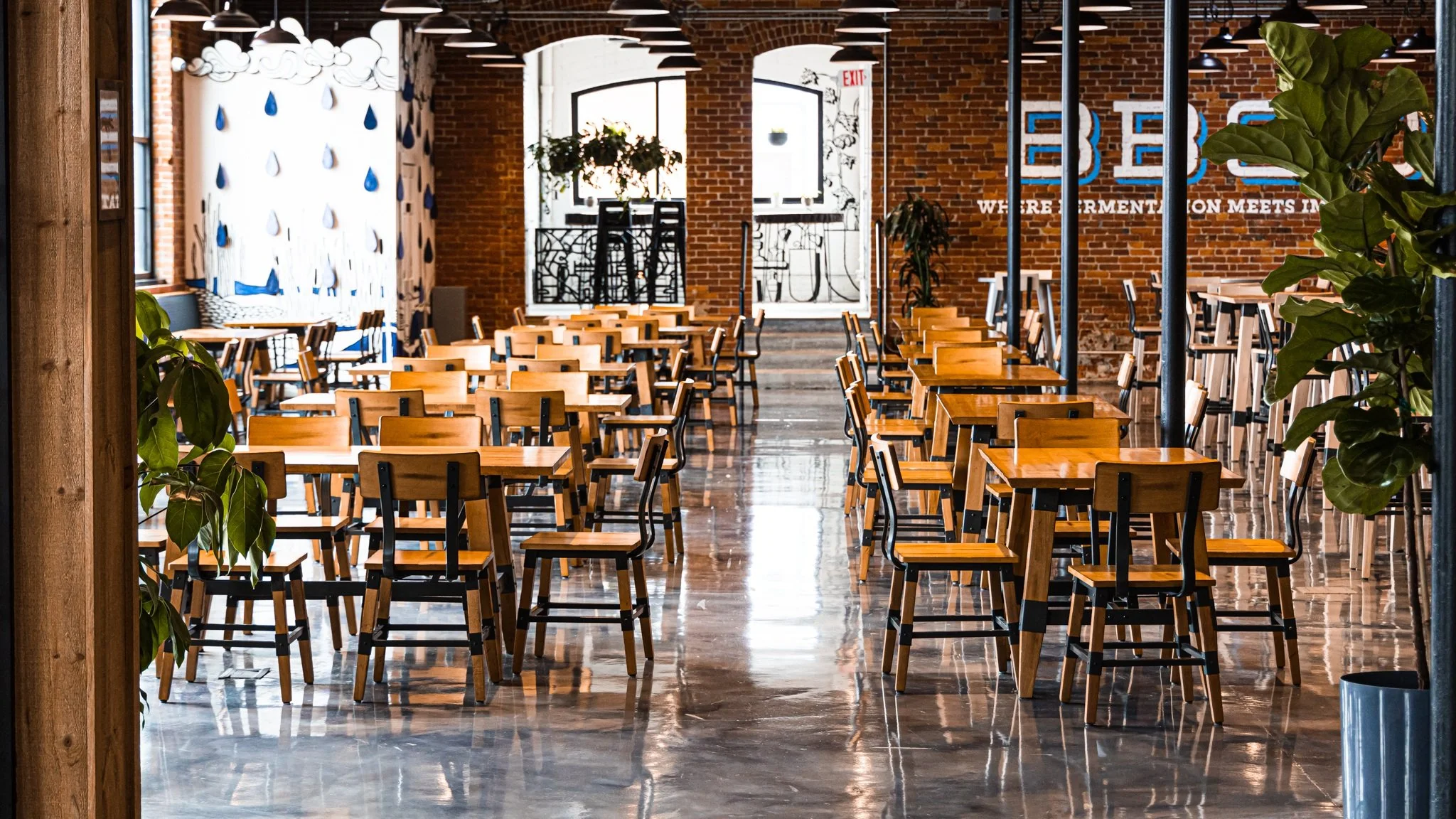 The finished Flynn Avenue dining room with tables, chairs, brick walls and pendant lights.