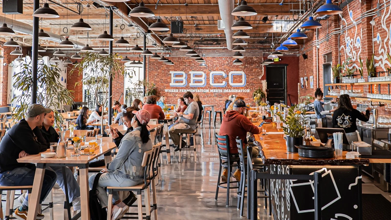 Guests sharing food and beer in Burlington Beer Co.’s bright Flynn Avenue taproom