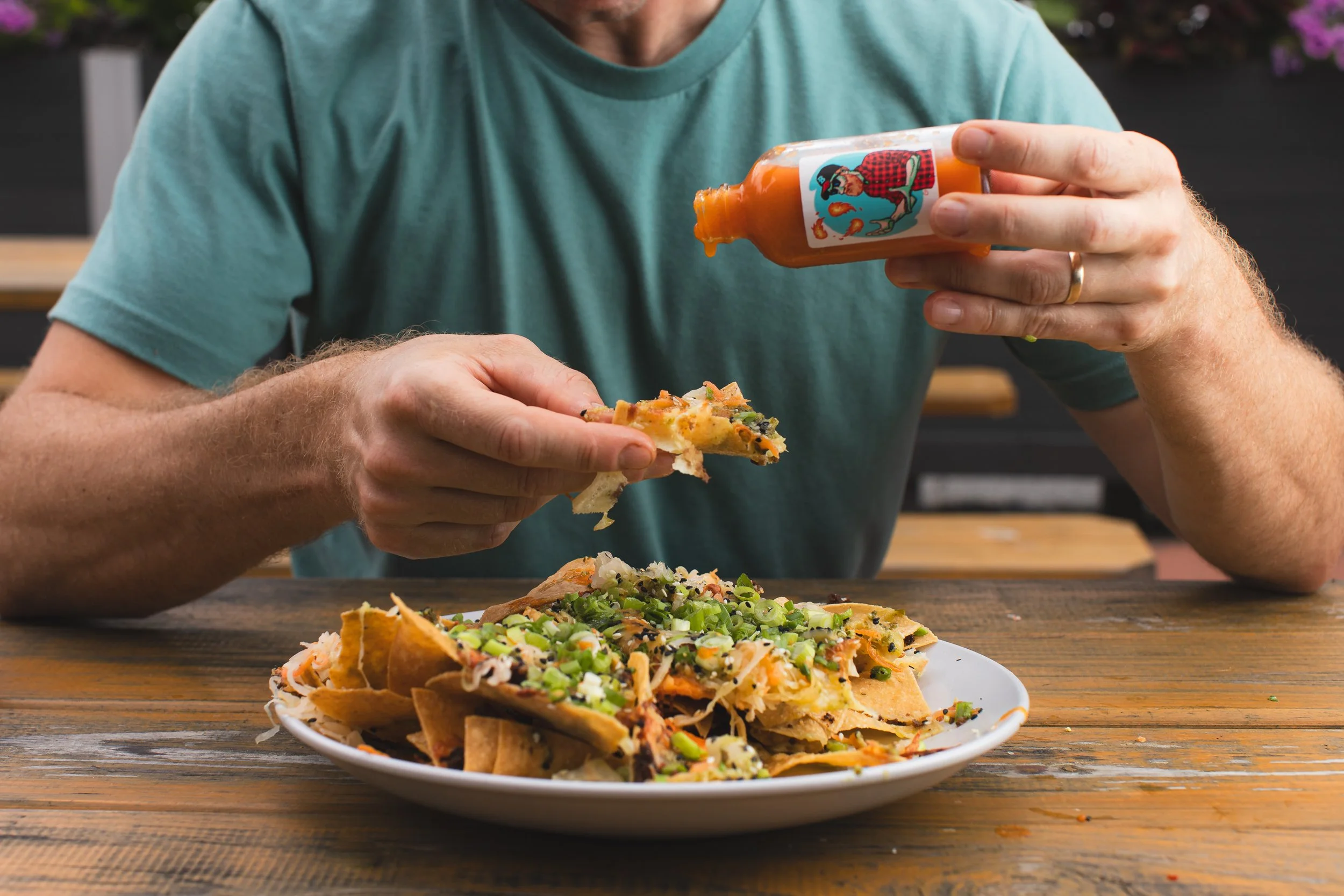 A guest adding hot sauce to nachos at Burlington Beer Co.