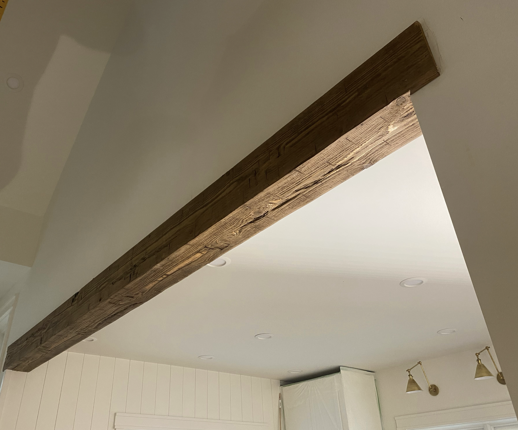 Ceiling with recessed lights and a wooden beam, part of a room interior.