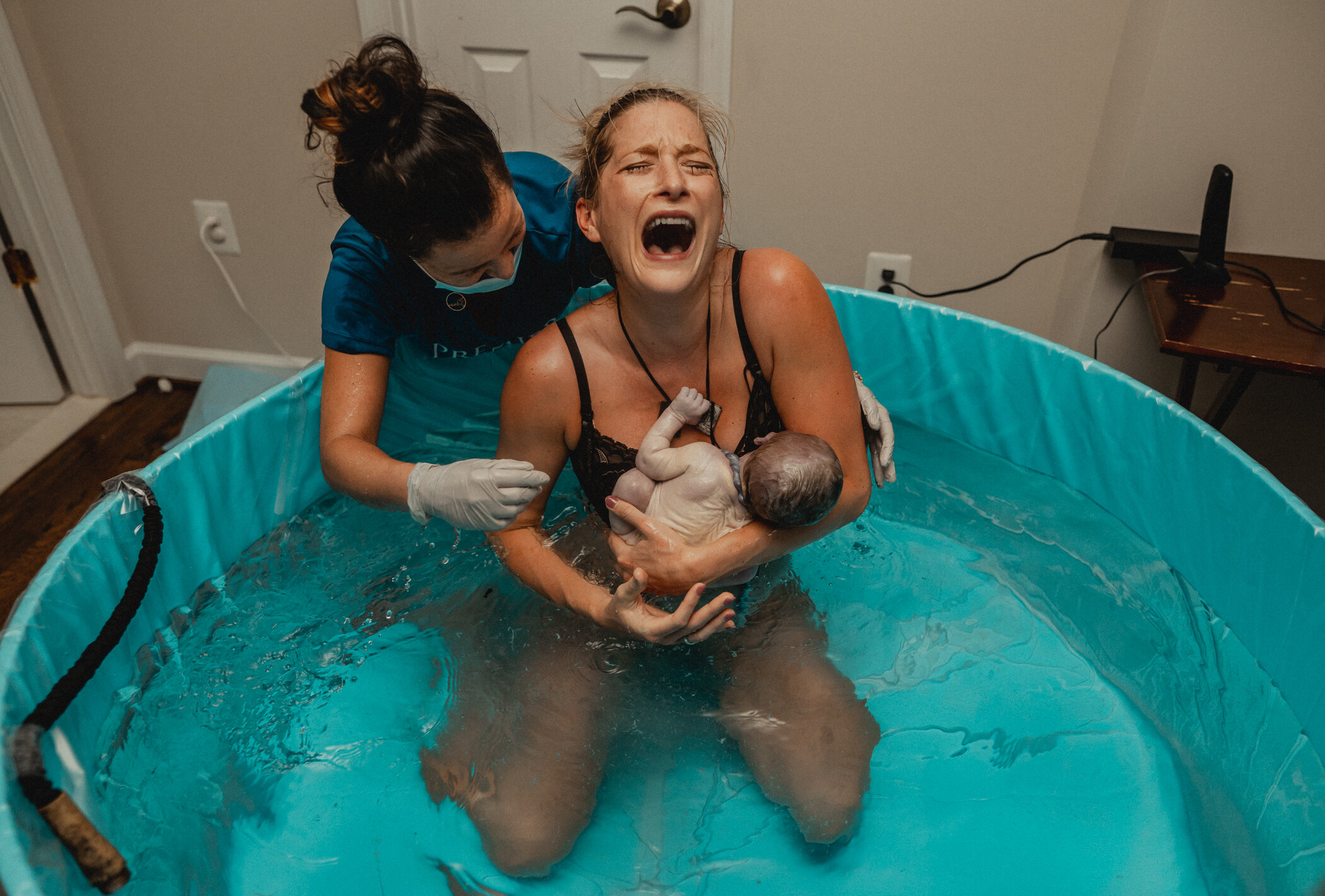 Woman has just birthed her baby in the birth tub during her Great Falls, VA home birth and let's out a big sigh of relief and joy while her baby is laying on her chest