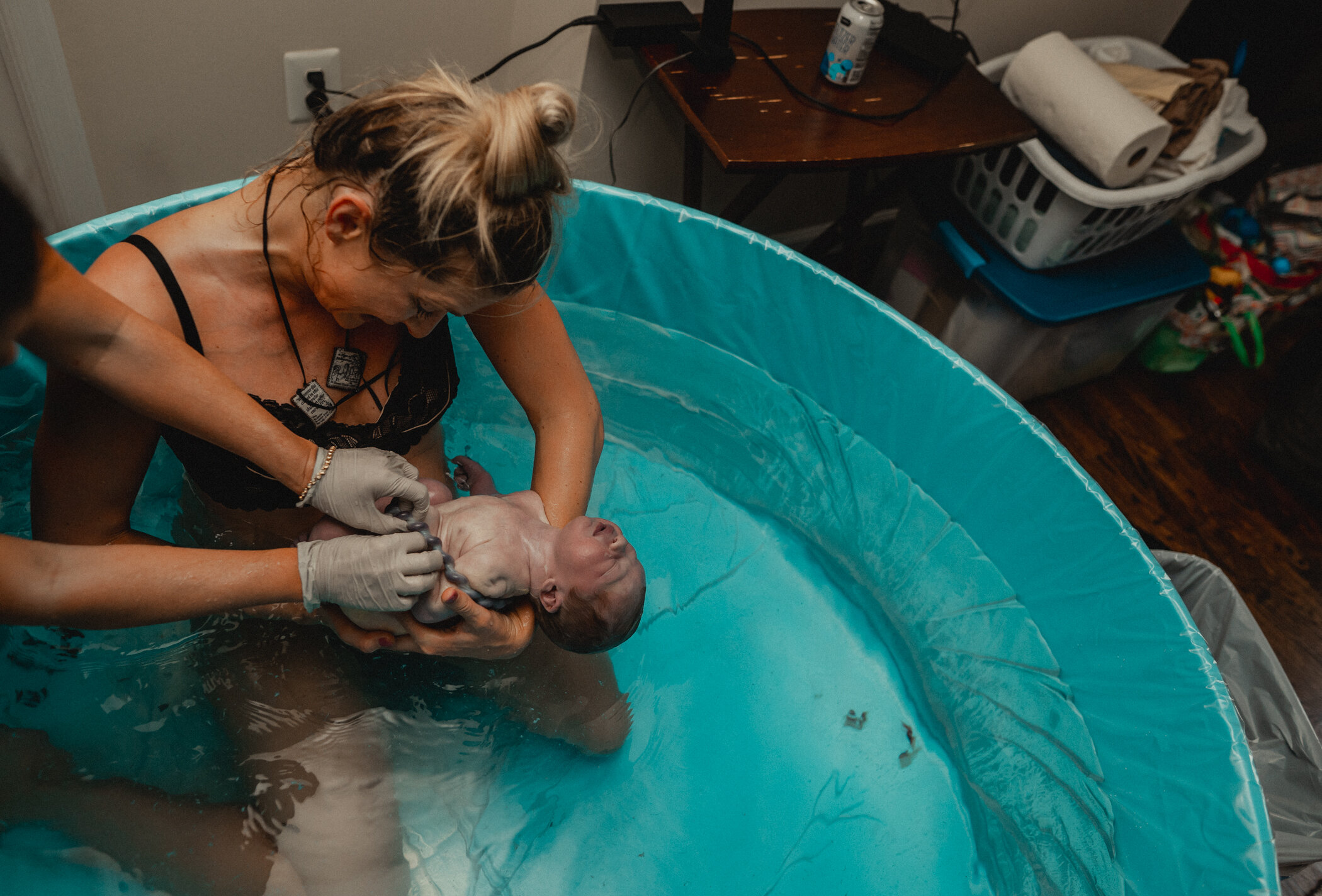 Women inspecting the gender of the baby after she delivered him in the birth tub during their Great Falls, VA home birth. Her midwife is behind her helping out with the nuchal cord