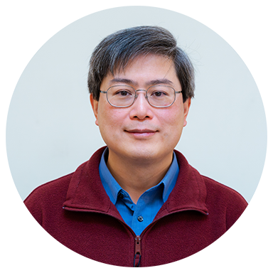 Person wearing glasses, red jacket, and blue shirt, on a neutral background.