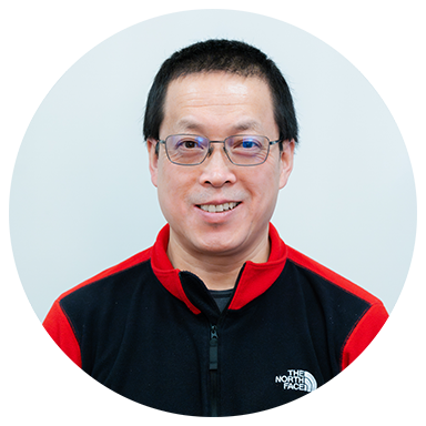 Man wearing glasses and a black and red North Face jacket, smiling, against a light background.