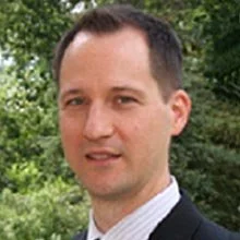 Man in suit with a blurred green foliage background