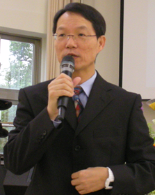 Person in suit speaking into a microphone indoors