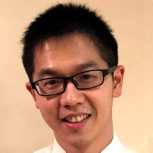 Smiling person with short dark hair and glasses