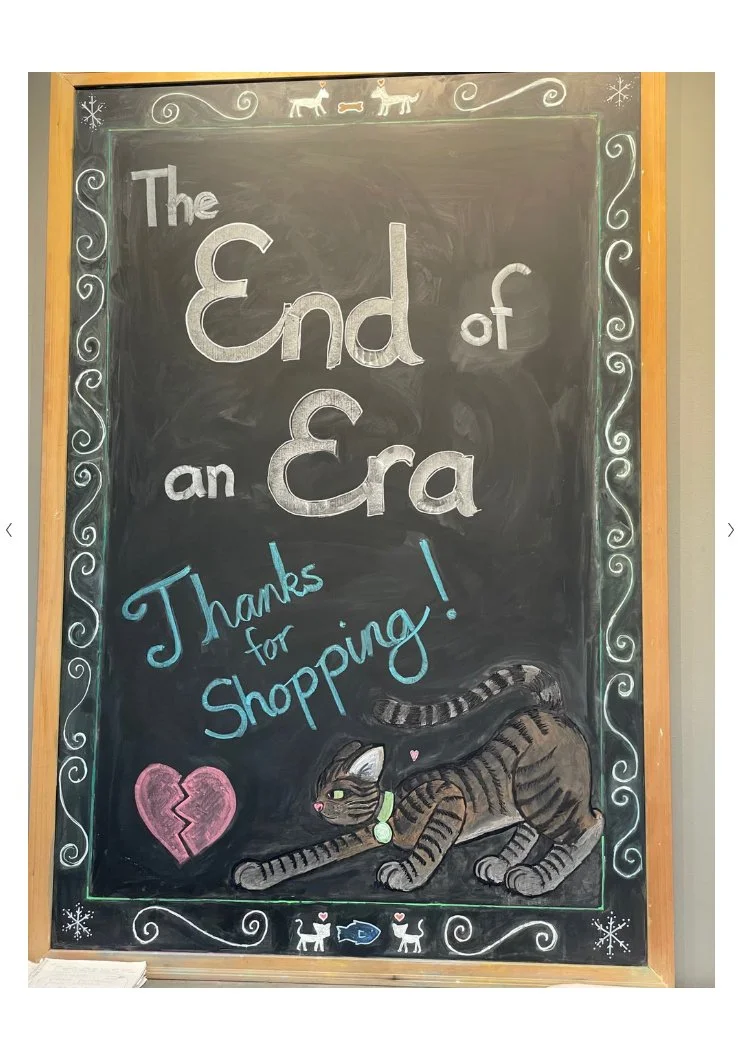 A chalkboard proclaims, "The End of an Era". Below that, it says, "Thanks for Shopping" in the "That's All Folks" font from Looney Tunes,  along with a broken heart, and a drawing of a tabby cat.