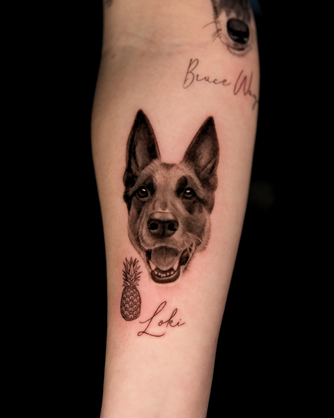 Black and grey German Shepherd portrait tattoo photographed on the inner forearm.