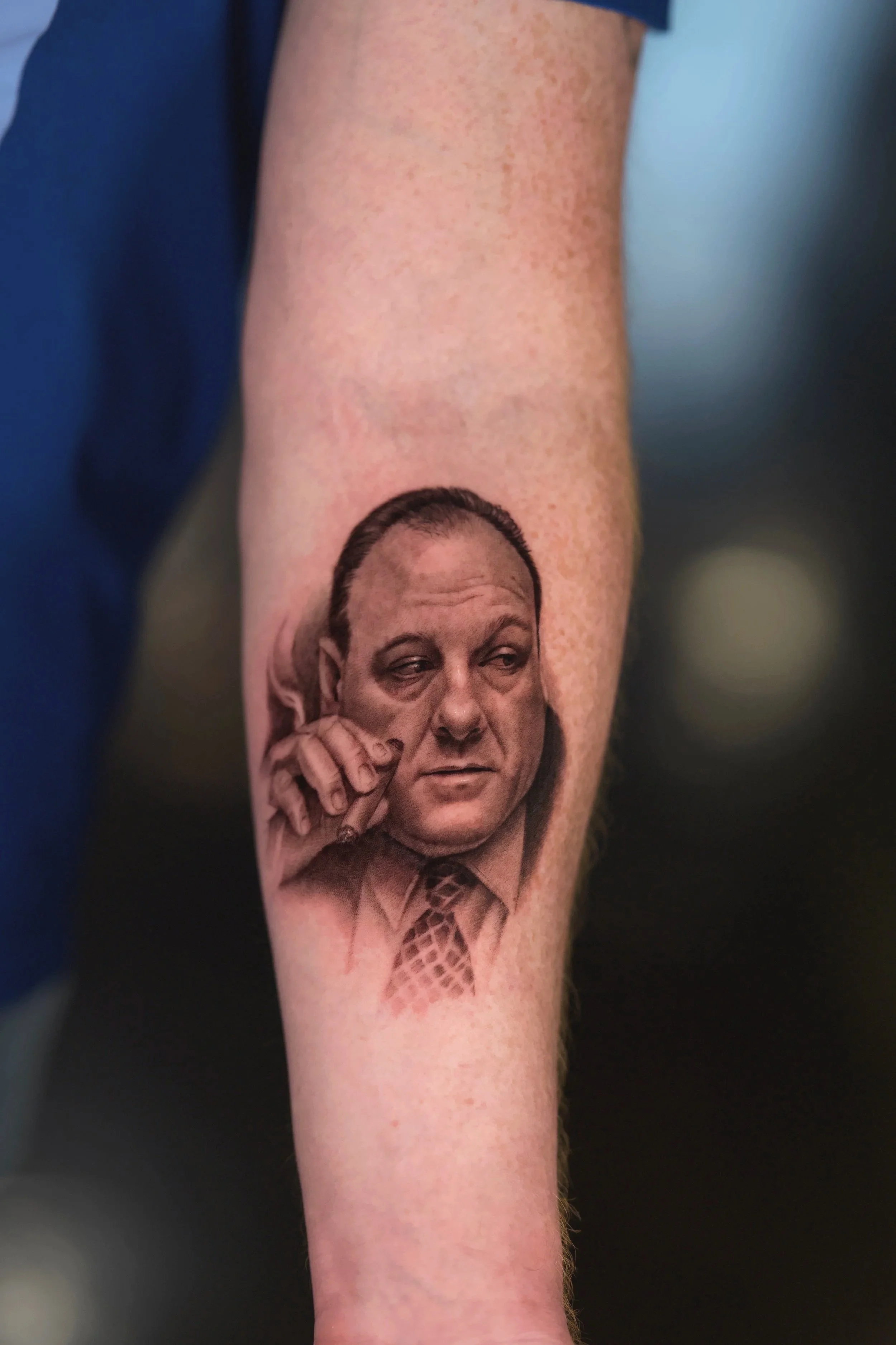 Realistic black and grey portrait celebrity tattoo of Tony Soprano, contemplative expression, inner forearm.