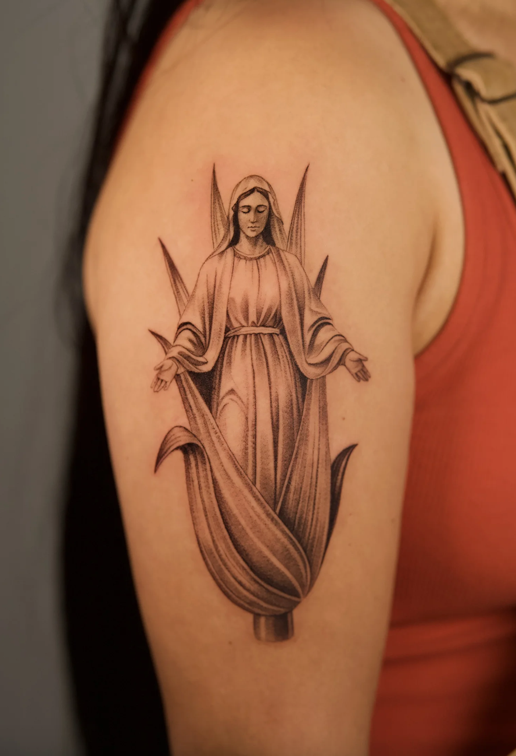 Fine line black and grey Virgin Mary tattoo in realistic microrealism style, inspired by corn imagery, tattooed on the upper arm by Brian Parrillo at Ethereal Tattoo Gallery in Durham, North Carolina.