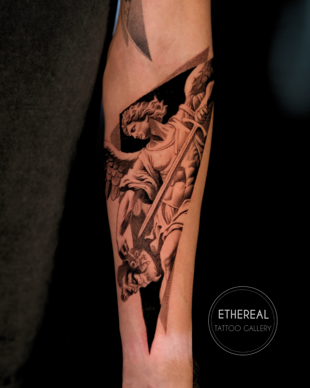 Fine line black and grey Archangel Saint Michael tattoo in realistic microrealism style, depicting Saint Michael defeating a demon, tattooed on the forearm by Brian Parrillo at Ethereal Tattoo Gallery in Durham, North Carolina.