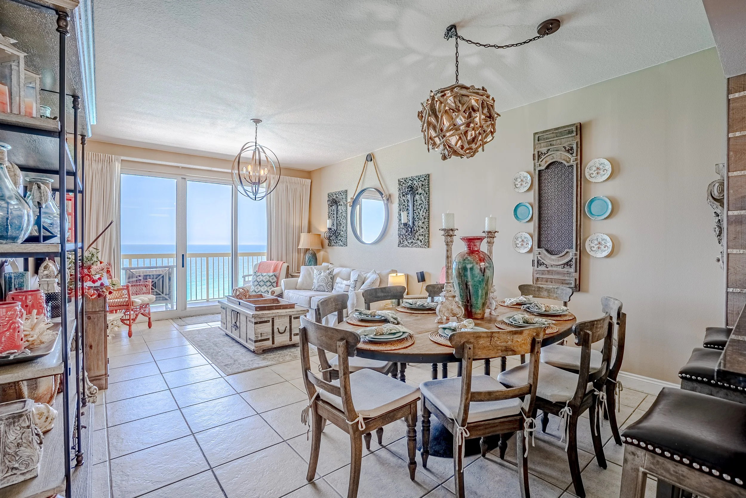 Living and dining area with sliding glass door leading to a balcony or patio, decorated with rustic and coastal-themed furniture and artwork.