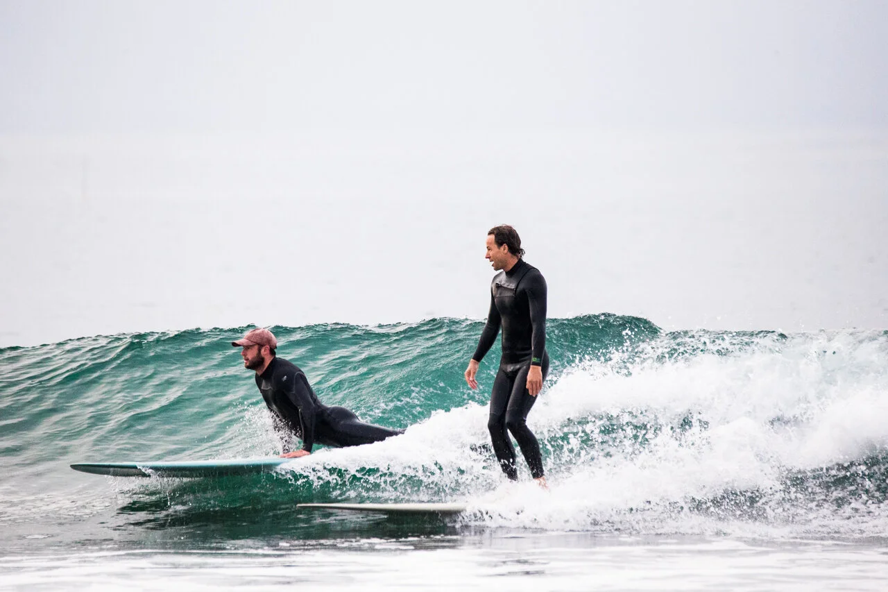 Surf photography capturing two surfers riding a wave off the California coast.