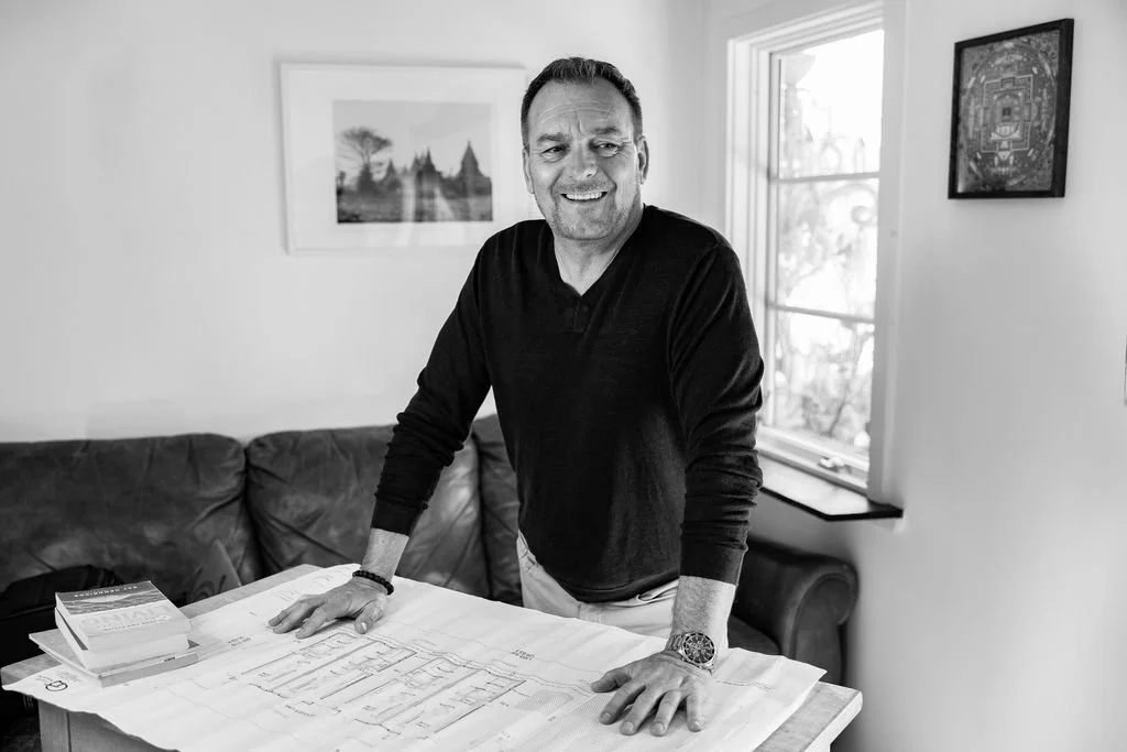 Environmental portrait of an architect photographed indoors with design plans.