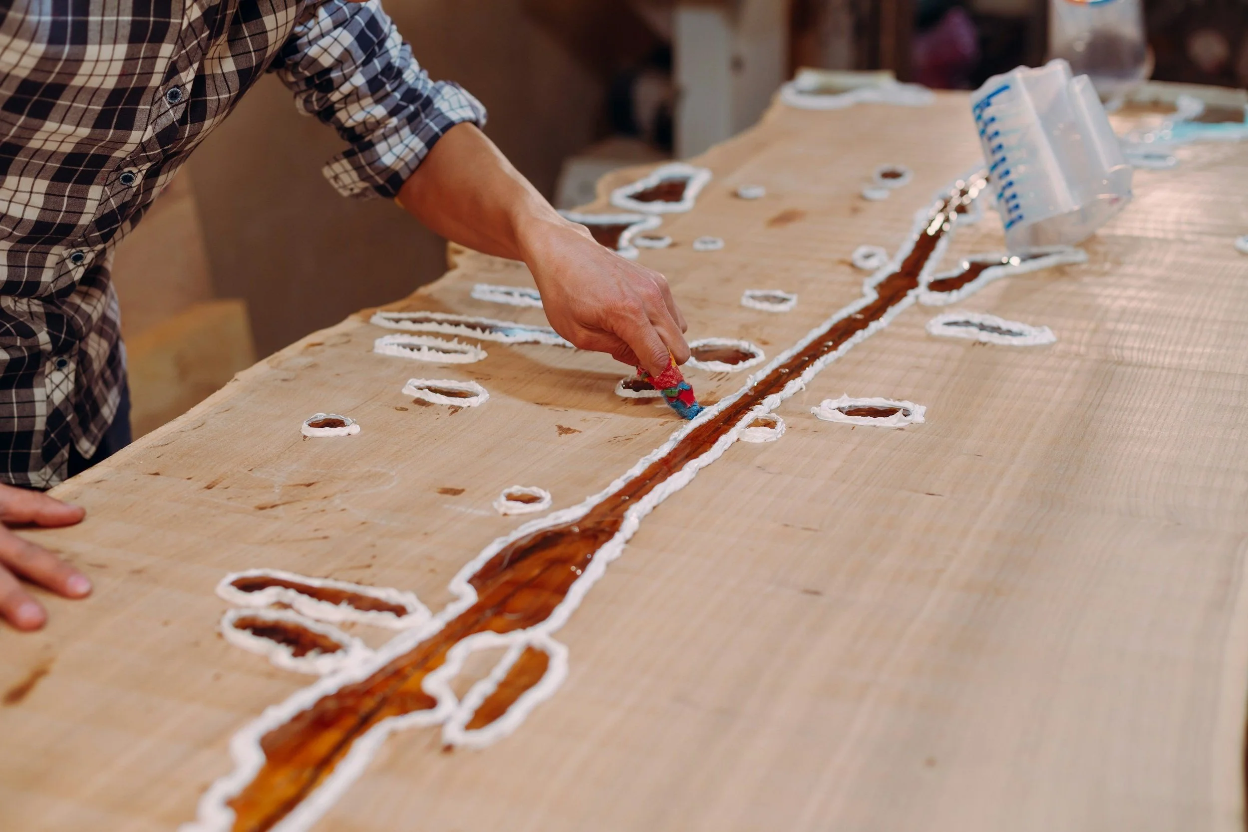Person working on a wooden table with cutouts and inlay in the shape of a Mickey Mouse design.