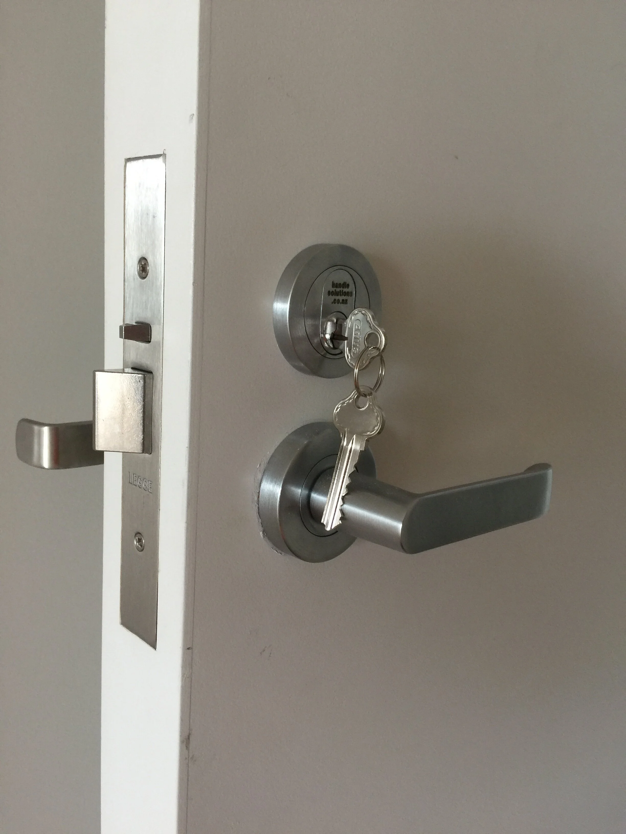 A door with a lockset and a key inserted in the lock.