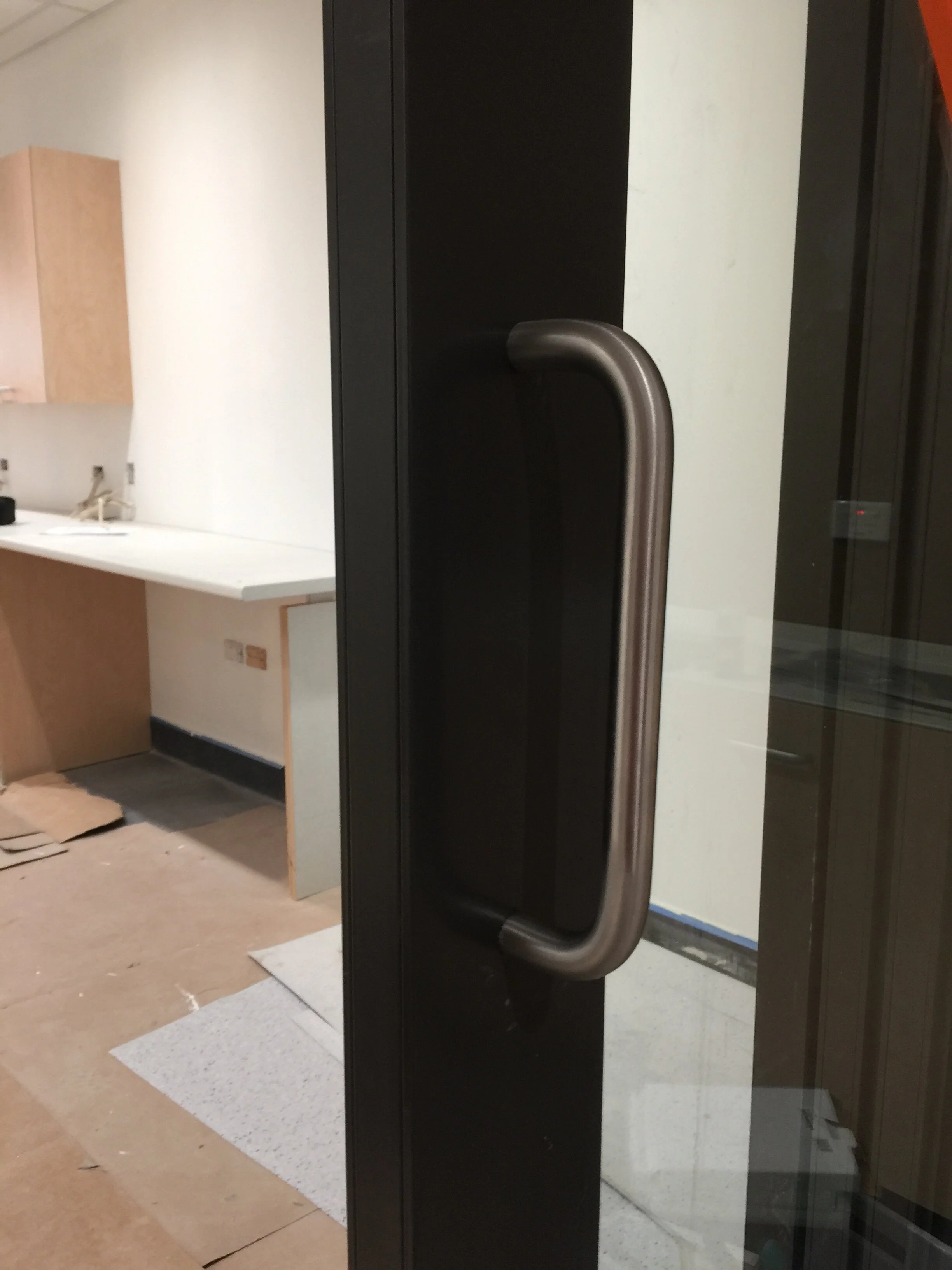 Close-up of a black glass door with a brushed metal handle.