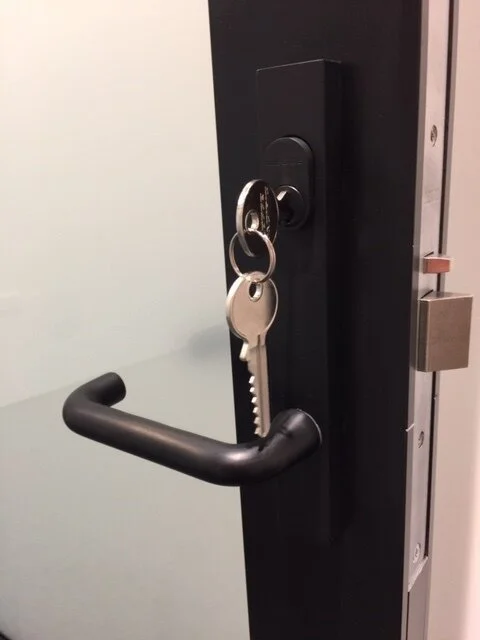 Door with a black handle and a key with a keychain hanging in the lock