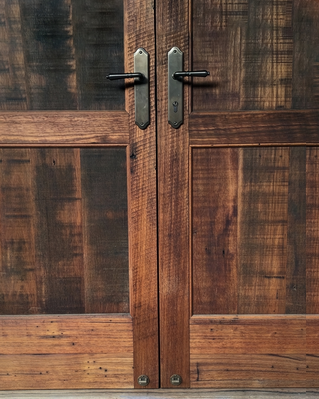 Close-up of wooden cabinet doors with black handles and metallic lock plates.