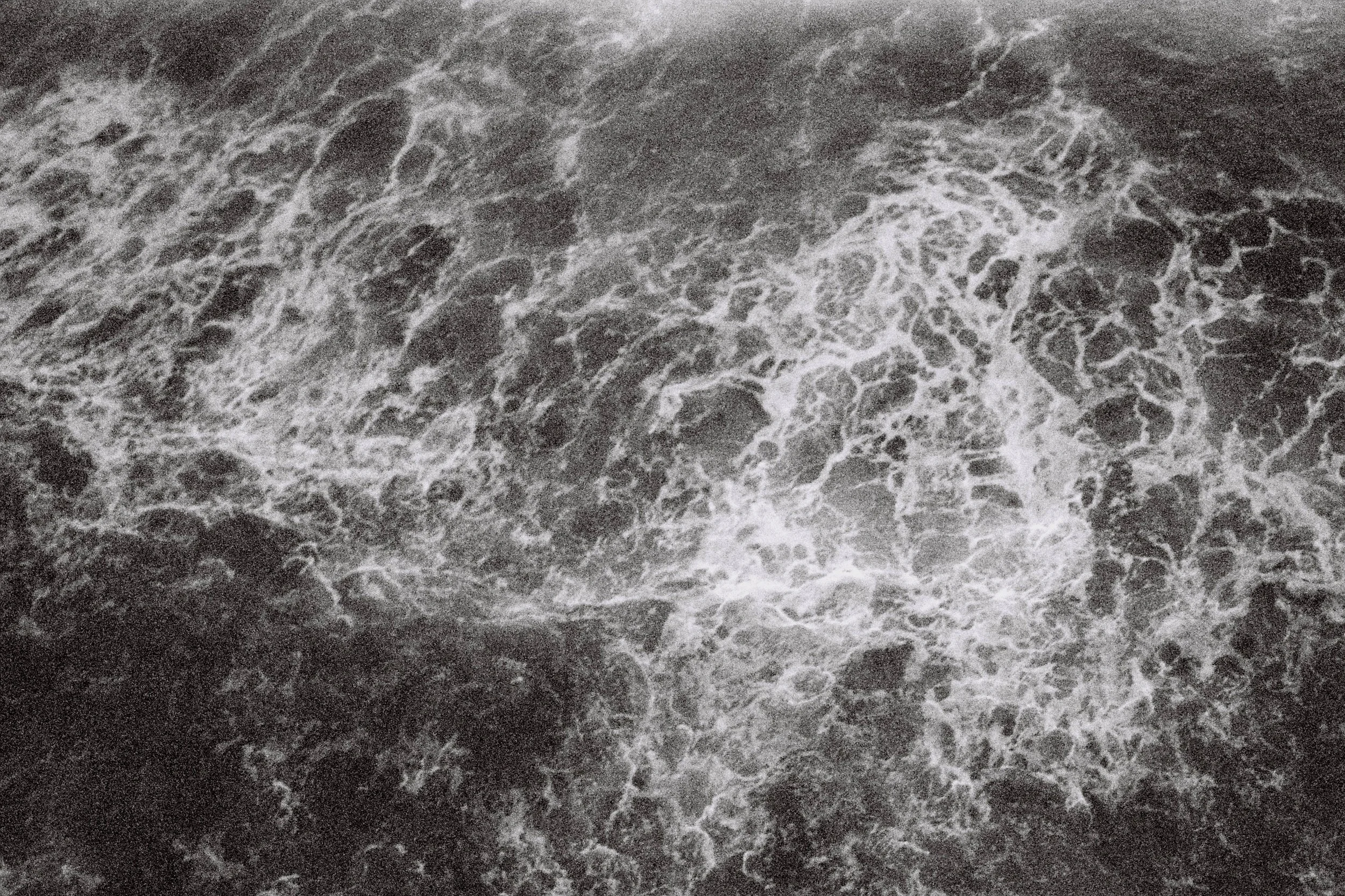 Close-up view of turbulent ocean waves with white foam on dark water surface.