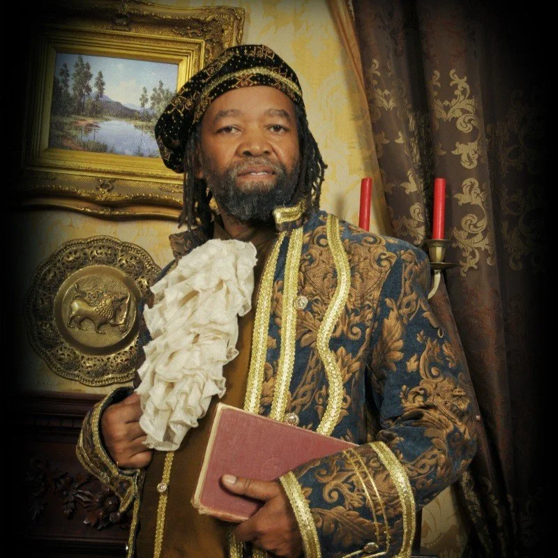 Person in elaborate vintage costume holding a book with a decorated background.