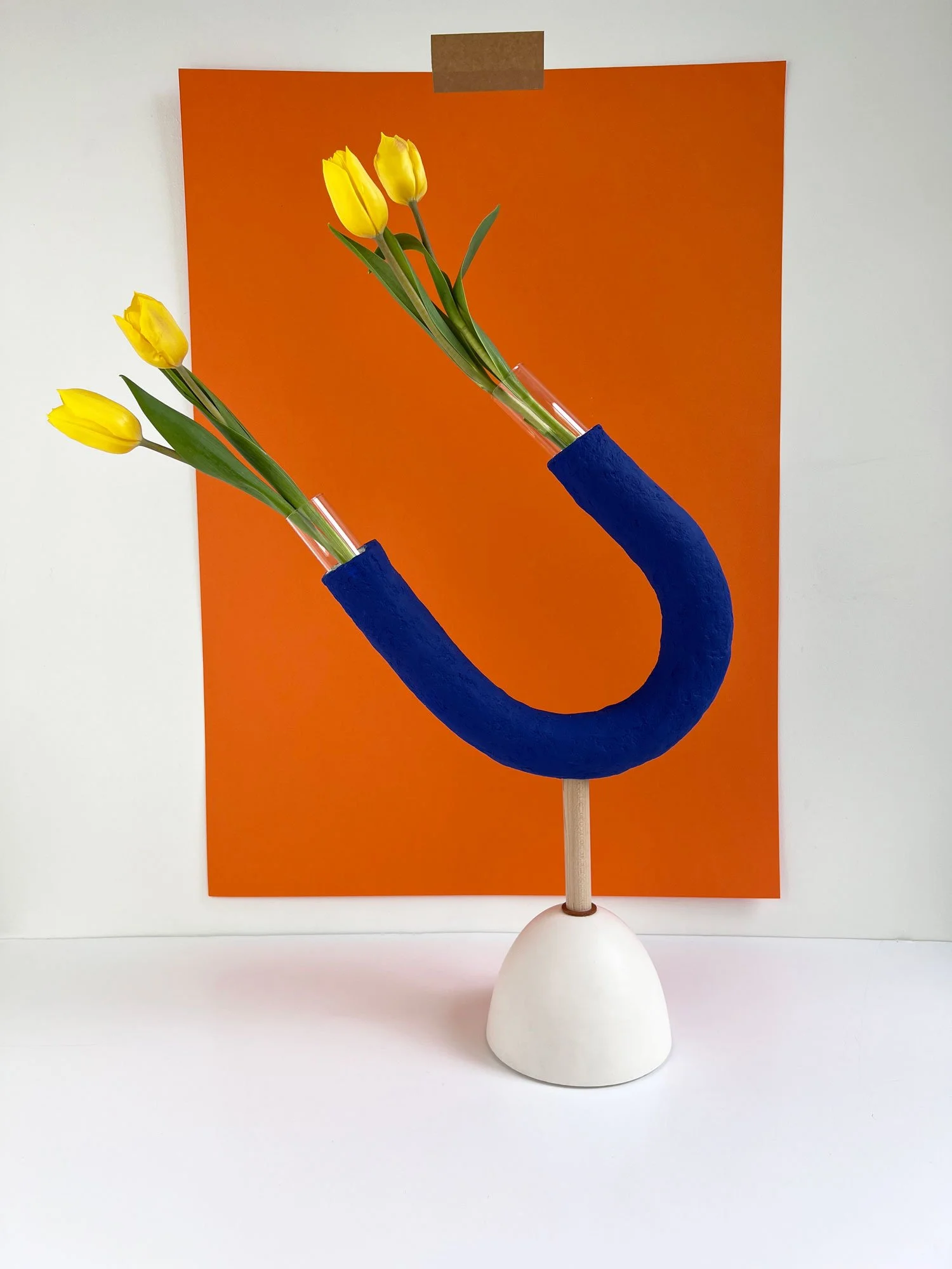 Contemporary tubular paper pulp vase painted electric blue with a glass test tube each end for flowers mounted on a white Jesmonite eco-resin base