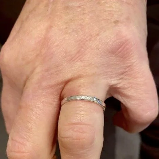 Close-up of a hand with a silver ring on the middle finger.