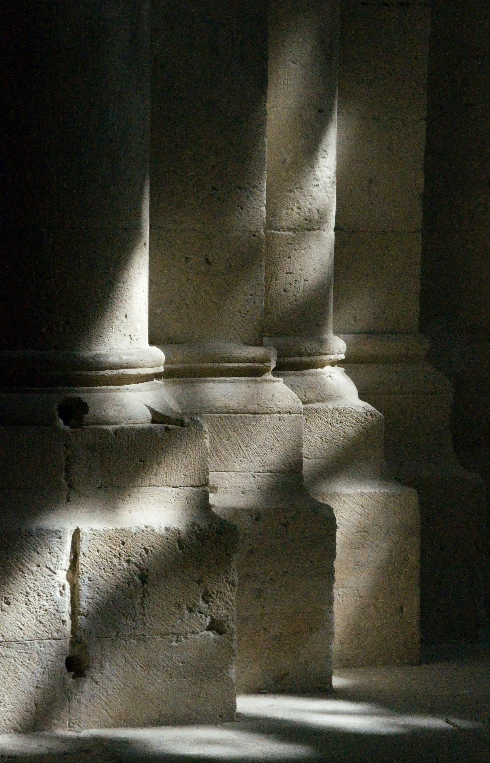 Stone columns and steps with patches of sunlight creating alternating light and shadow.