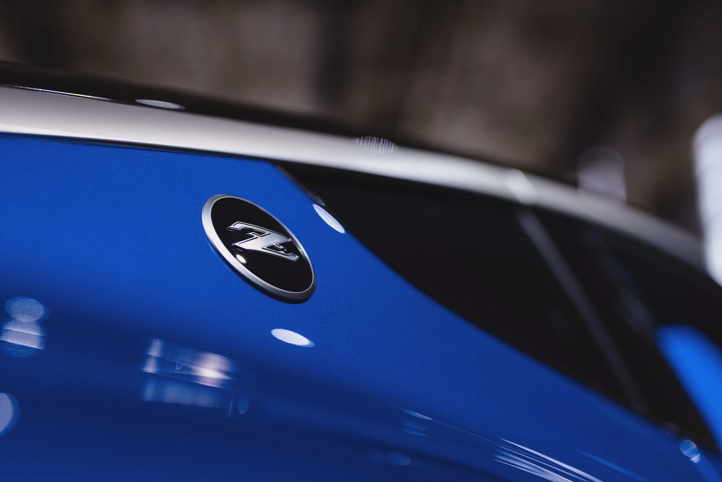 Close-up of a blue car featuring a round emblem with a "Z" on the side panel.