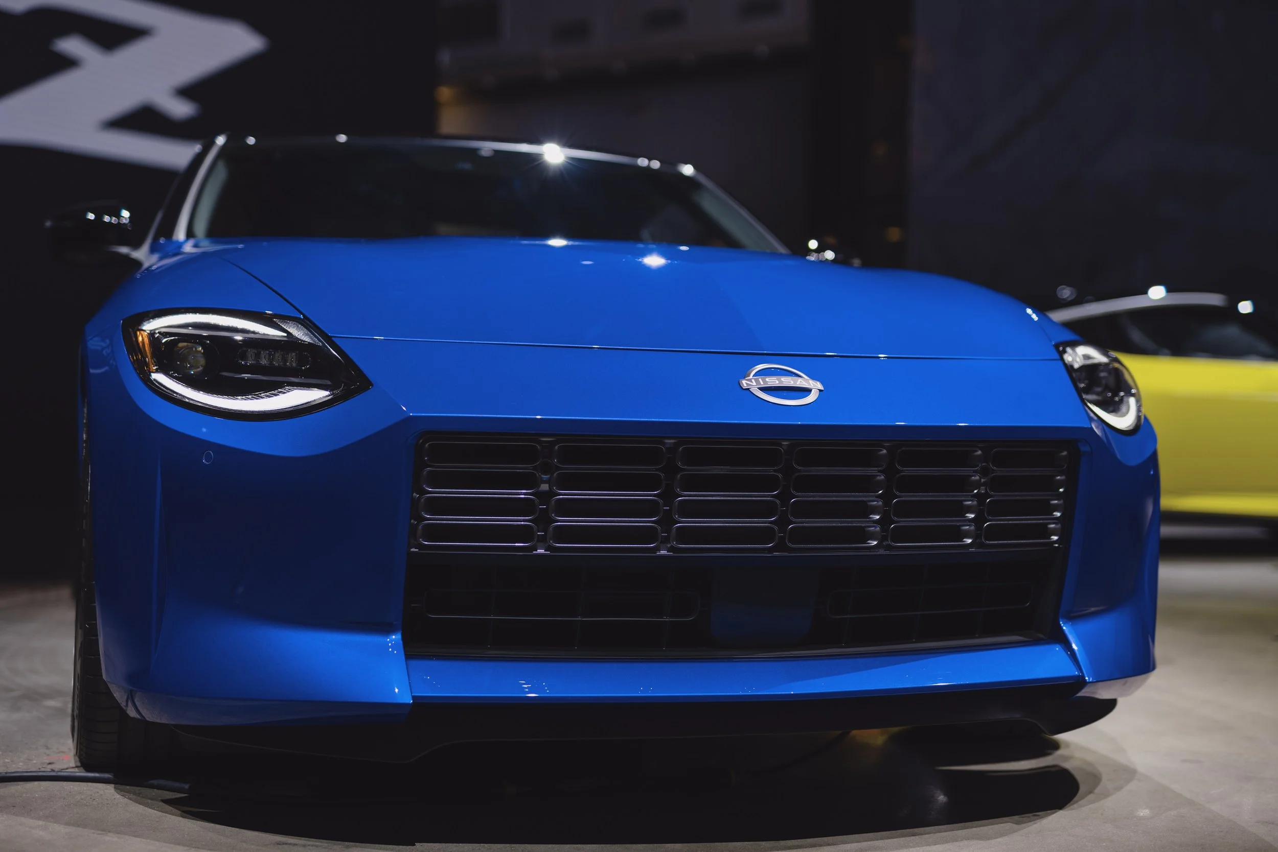 Front view of a blue Nissan sports car with distinctive headlights and grille, showcased indoors.